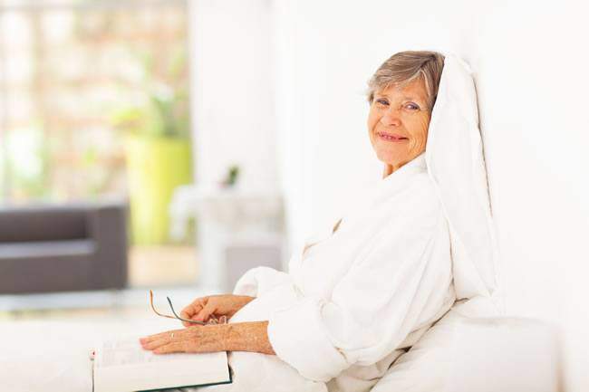 Elderly Woman Reading Book In Bed